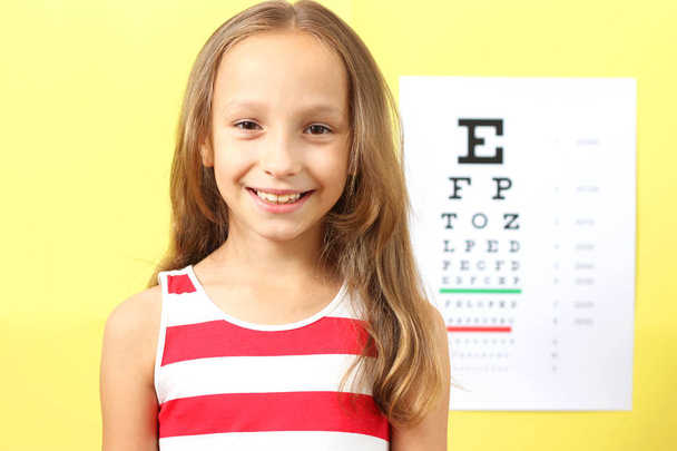 little cute cheerful girl passes an eye test in the office of an ophthalmologist - Photo, Image