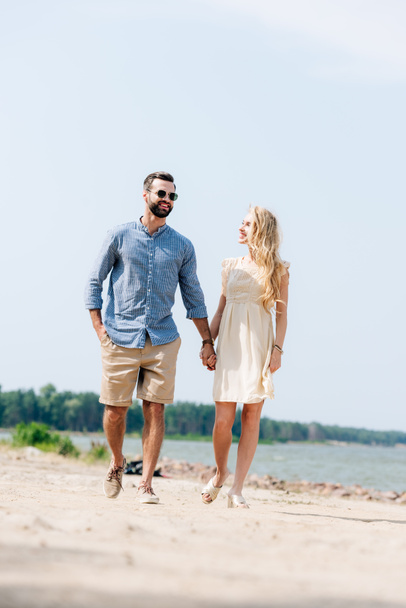 adult happy couple walking along beach and holding hands - Fotó, kép