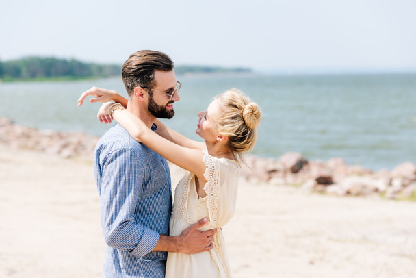 happy blonde woman hugging smiling bearded boyfriend at beach - Фото, зображення