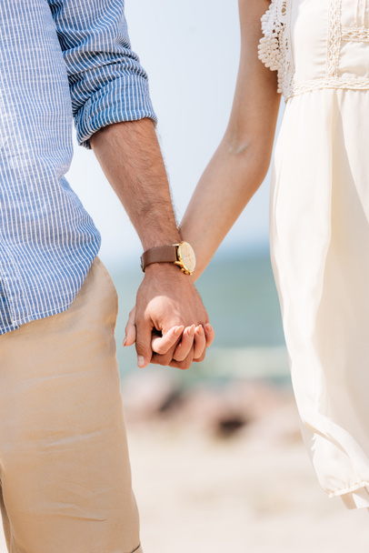 partial view of couple holding hands at beach in sunlight - Foto, Imagem