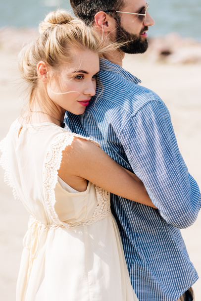 young blonde woman hugging bearded boyfriend at beach - Фото, зображення