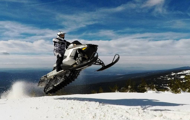 Rider Man z kask skoki z Snowmobile na szczycie w zimie  - Zdjęcie, obraz