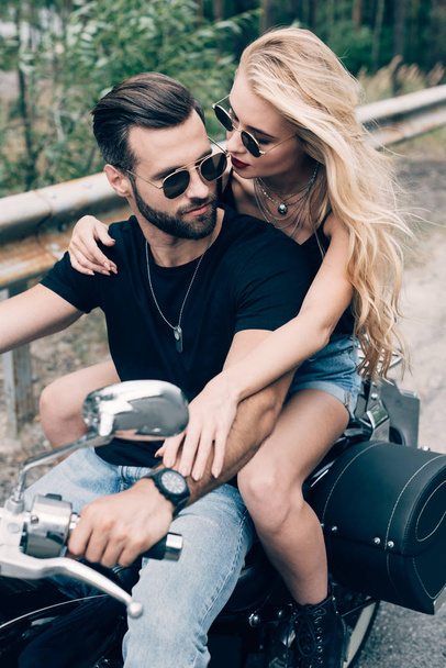 young couple of bikers closely embracing on black motorcycle - Fotoğraf, Görsel