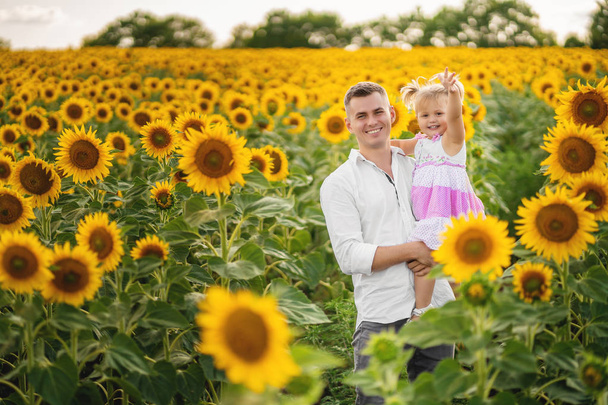 Father with daughter on the sunflower field. - Φωτογραφία, εικόνα