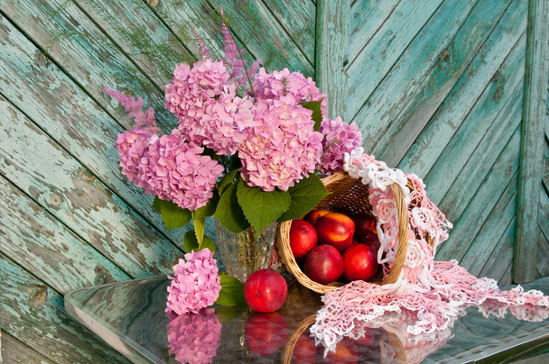 Still life with hydrangea and basket of nectarines on the old wooden wall background - Photo, Image