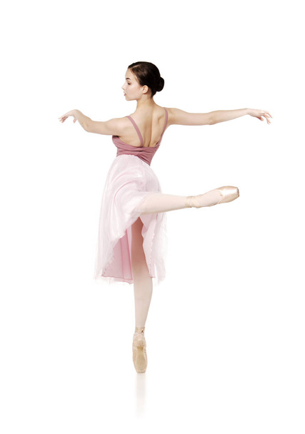 Elegant girl in a pink skirt and beige top dancing ballet. - Foto, imagen