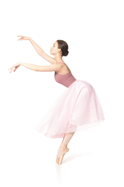 Elegant girl in a pink skirt and beige top dancing ballet. - Fotó, kép