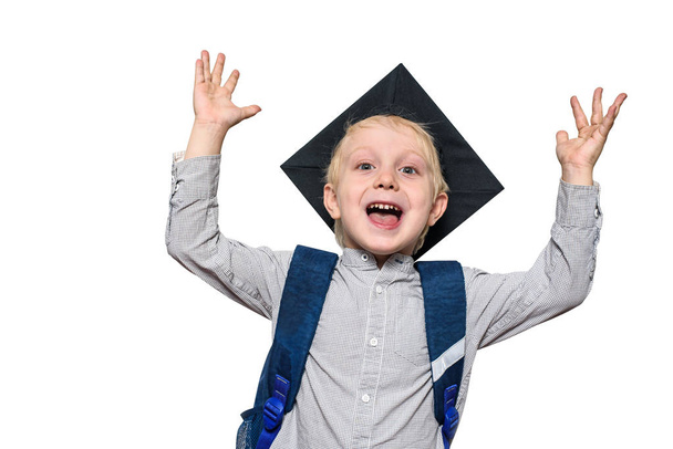 Portré egy örömteli szőke fiú akadémiai kalap és egy iskolai táska. Kezeket fel. Elkülöníteni - Fotó, kép