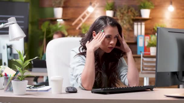 Stressed woman having a headache while working in the office - Filmati, video