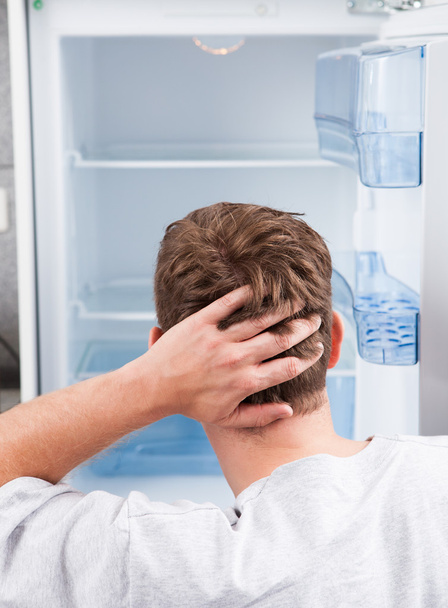 Thoughtful man looking in empty refrigerator - Foto, Bild