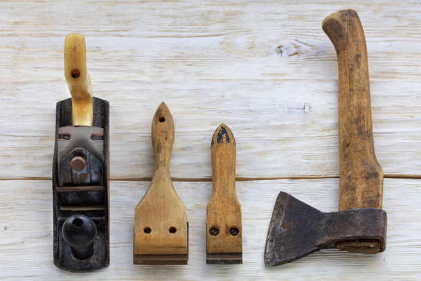 Παλιά εργαλεία ξυλουργικών βρίσκονται σε ένα λευκό ξύλινο τραπέζι. - Φωτογραφία, εικόνα