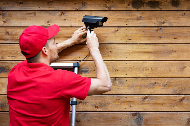 home security - man installing outdoor surveillance camera on wo - Photo, Image