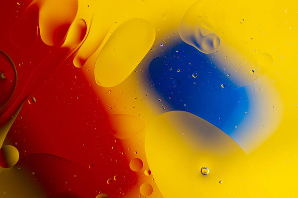 Abstract oil spots in motion on water on blurred yellow backgrou - Foto, imagen