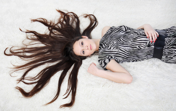 beautiful girl with long hair wearing striped dress lies on whit - Fotó, kép