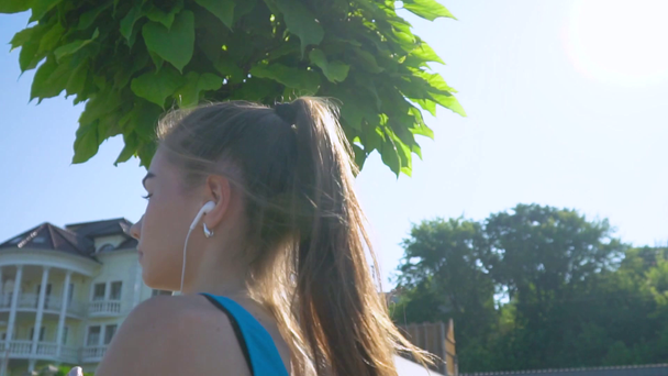 Genç kız koşuyor ve parkta müzik dinliyor. Çağdaş kadınların sağlıklı yaşam tarzı, kilo kaybı ve formda tutmak - Video, Çekim