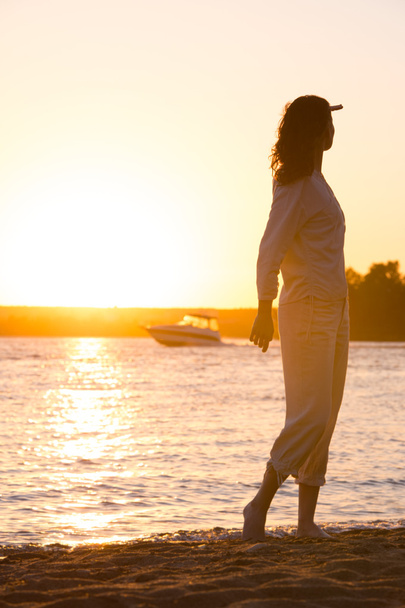 Hermosa mujer en camisa blanca natural mirando al sol dorado
 - Foto, imagen