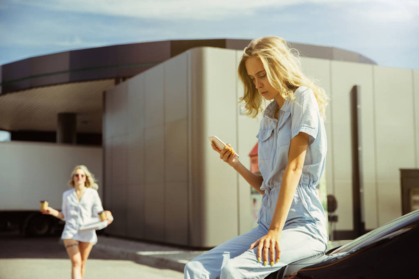 Young lesbians couple preparing for vacation trip on the car in sunny day - Фото, зображення