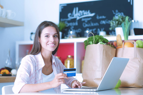 Smiling woman online shopping using tablet and credit card in kitchen . Smiling woman - Foto, Imagen