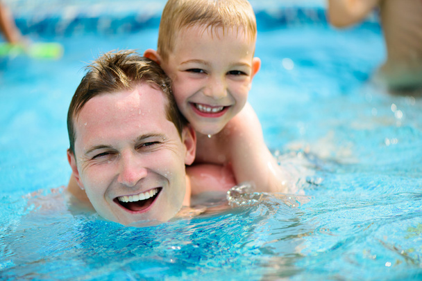 Young father and little son swimming in pool - Foto, imagen