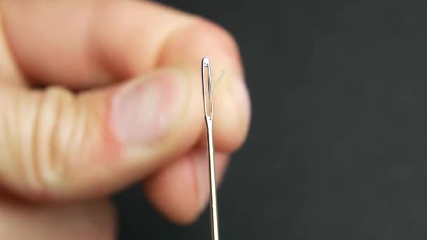 Mans hand holds needle and white thread. Start of sewing - Footage, Video