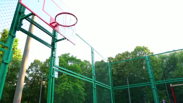 Kosárlabda játékos a szabadban kosarazik. Egy fiatalember kosárlabdával ugrik, hogy ringbe szálljon. Sport motiváció, edzés a szabadban. - Felvétel, videó