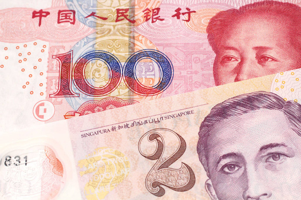 Een close-up afbeelding van een rode, 100 yuan bankbiljet van de Volksrepubliek China, in macro met een twee dollar Bill uit Singapore - Foto, afbeelding