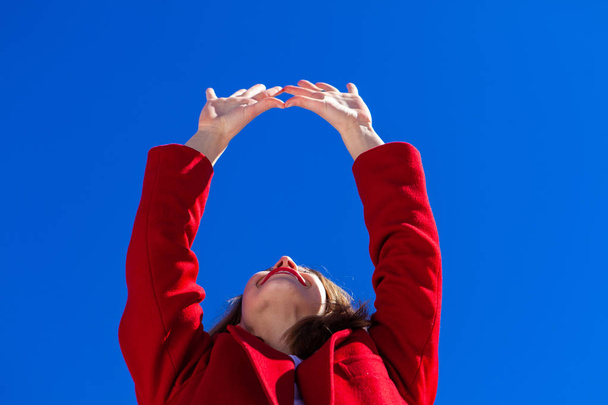 Happy lady stretches arms to blue sky. - Photo, Image