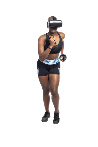 Black African American kobieta działa w VR podczas noszenia zestaw słuchawkowy wirtualnej rzeczywistości do treningu lub grania w gry wideo. Przedstawia technologię i sport oraz e-sporty.   - Zdjęcie, obraz