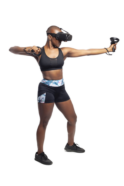 Black female wearing virtual reality headset pretending to draw a bow and playing a VR archery video game.  She is aiming at a target. Depicts esports.  - Fotó, kép
