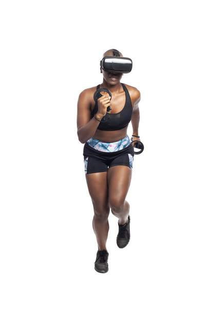 Black African American kobieta działa w VR podczas noszenia zestaw słuchawkowy wirtualnej rzeczywistości do treningu lub grania w gry wideo. Przedstawia technologię i sport oraz e-sporty.   - Zdjęcie, obraz
