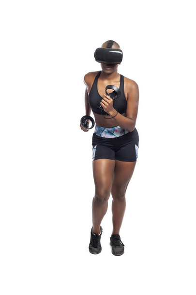 トレーニングやビデオゲームをプレイするためのバーチャルリアリティヘッドセットを身に着けている間、Vrで実行している黒人アフリカ系アメリカ人の女性。技術とスポーツとeスポーツを描く.   - 写真・画像