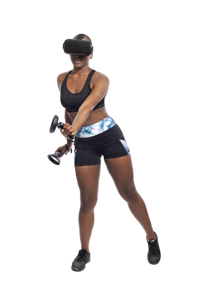 Black African American woman working out by playing a VR dancing rhythm video game while wearing a virtual reality headset.  Depicts esports technology and active lifestyle.  - Foto, Imagen