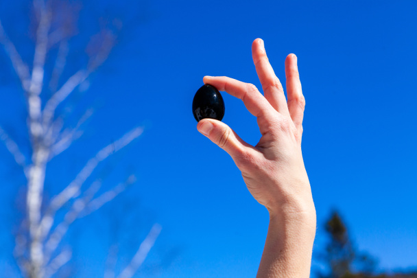 Lady holds yoni egg against clear sky. - Photo, Image