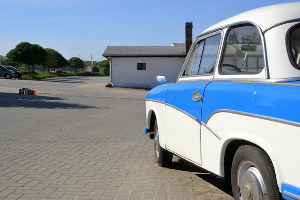 Sinivalkoinen klassinen auto tien varressa
 - Valokuva, kuva