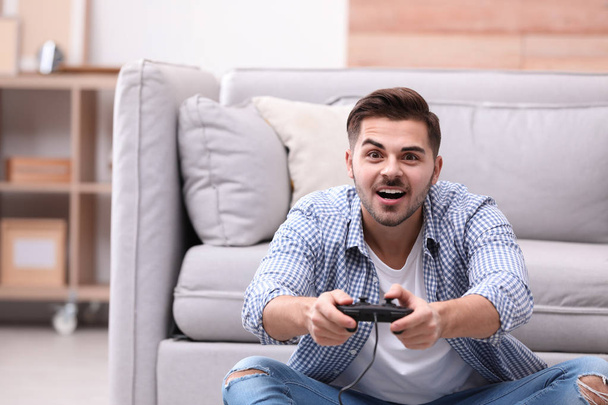 Emotional young man playing video games at home - Fotoğraf, Görsel