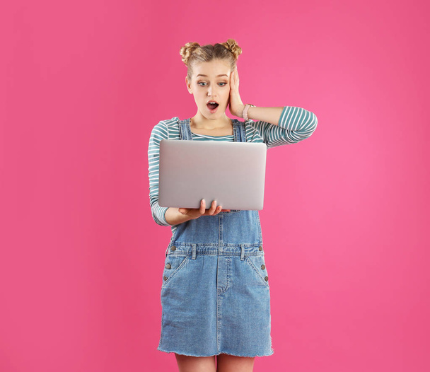 Portrait of young woman with laptop on pink background - 写真・画像