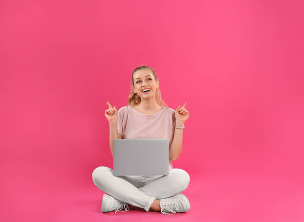 Beautiful young woman with laptop on pink background - Zdjęcie, obraz
