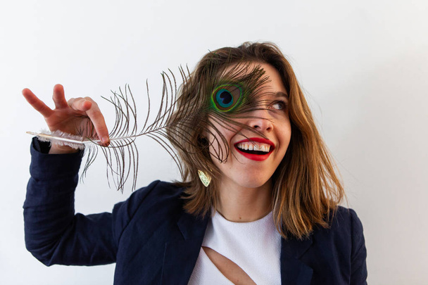 Chica juguetona sostiene pluma de pavo real
 - Foto, imagen