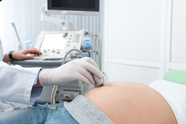 Nuori raskaana oleva nainen, jolle tehdään ultraäänitutkimus nykyaikaisessa klinikassa, lähikuva
 - Valokuva, kuva