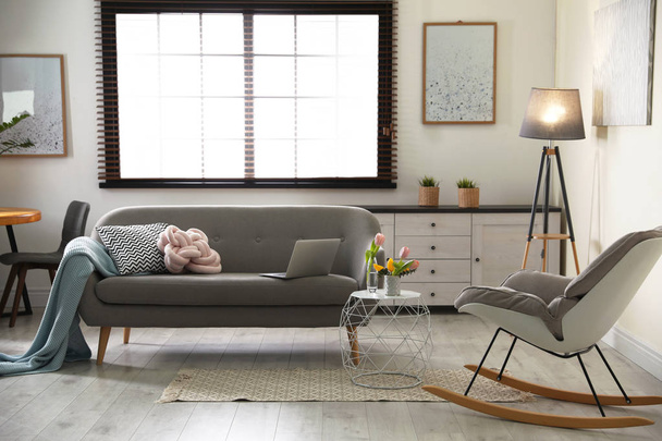 Interior de la acogedora sala de estar con sofá gris y mecedora
 - Foto, imagen