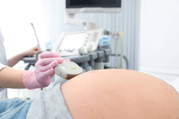 現代の診療所で超音波スキャンを受けている若い妊婦、クローズアップビュー - 写真・画像
