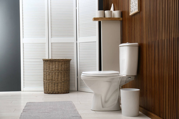 weiße Toilettenschüssel in der Nähe der Holzwand im modernen Badezimmerinnenraum - Foto, Bild