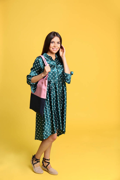 Full length portrait of young woman with textile bag on yellow background - Photo, image