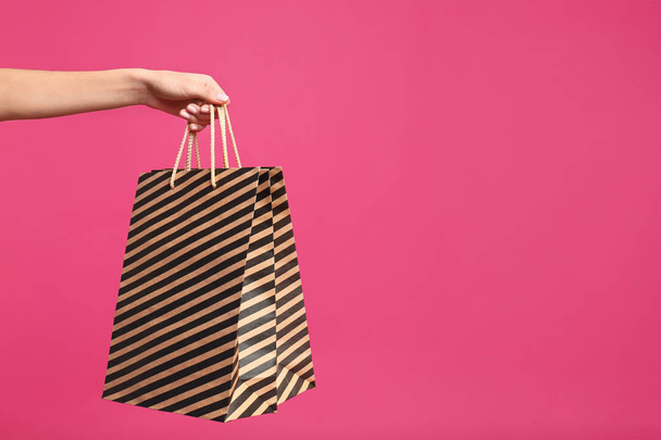 Young woman with paper bags on pink background, closeup. Space for text - Foto, afbeelding
