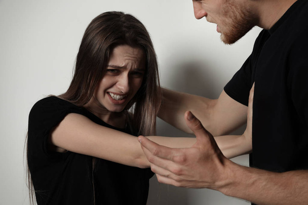 Man fighting with woman on light background. Stop sexual assault - Foto, Bild