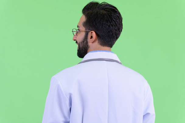 Vista trasera de cerca de feliz joven barbudo persa hombre médico sonriendo
 - Foto, Imagen