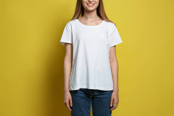Młoda kobieta nosi pusty t-shirt na żółtym tle, zbliżenie. Makieta do projektowania - Zdjęcie, obraz