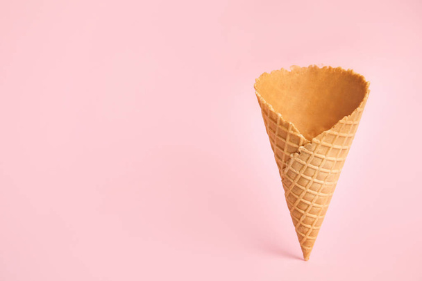 Empty wafer ice cream cone on pink background. Space for text - 写真・画像