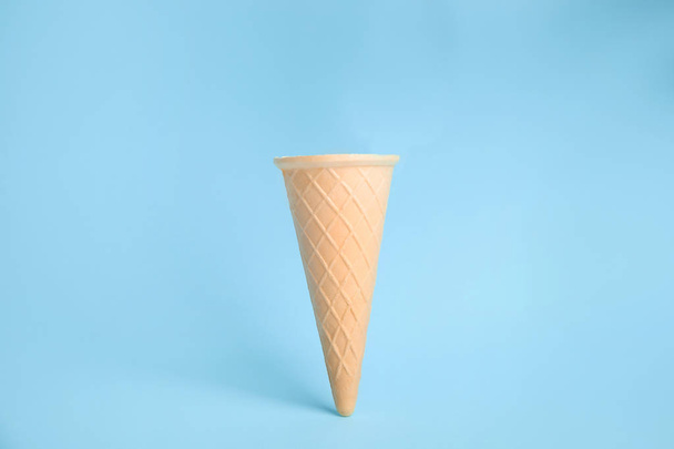 Empty wafer ice cream cone on blue background - Foto, afbeelding