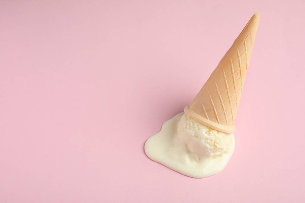 Melted vanilla ice cream in wafer cone on pink background, above view. Space for text - Photo, Image